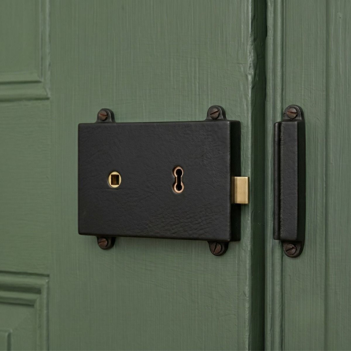 The Reversible "Bamburgh" Iron Rim Lock Mounted on a Green Wooden Door Entrance - Digital Illustration