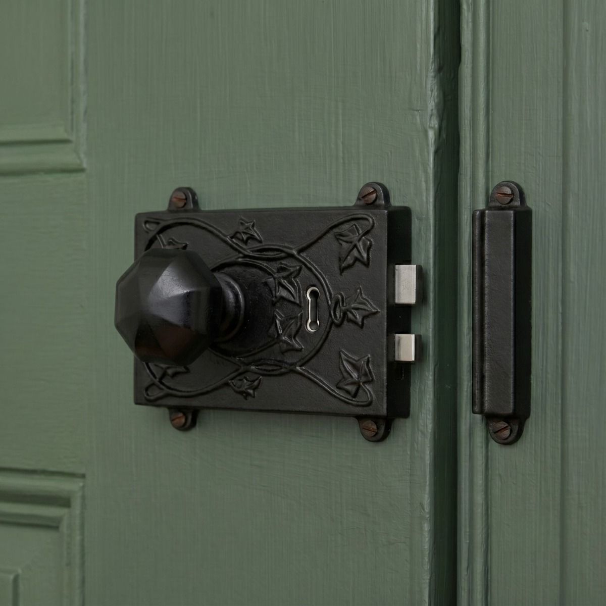 The Reversible "Brackenthorpe" Ornate Black Iron Rim Lock Shown Fitted on a Contemporary Wooden Door - Digital Illustration 