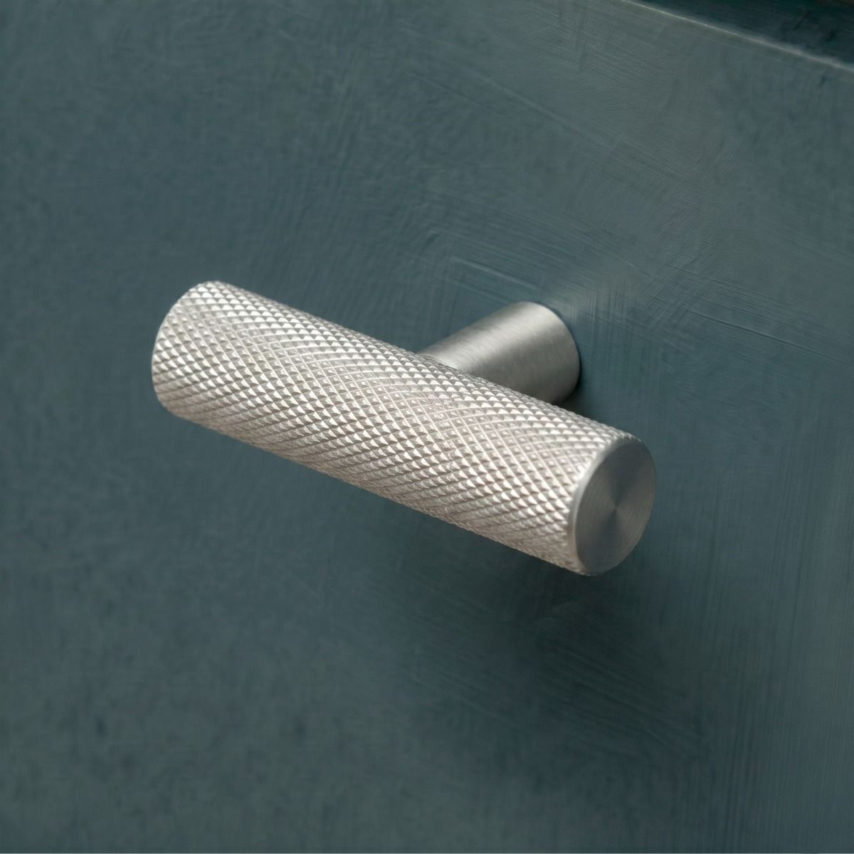 The Aged Brass "Astor" Knurled Industrial T-Bar Cabinet Handle Mounted on a Dark Blue Kitchen Cupboard Drawer - Digital Illustration 
