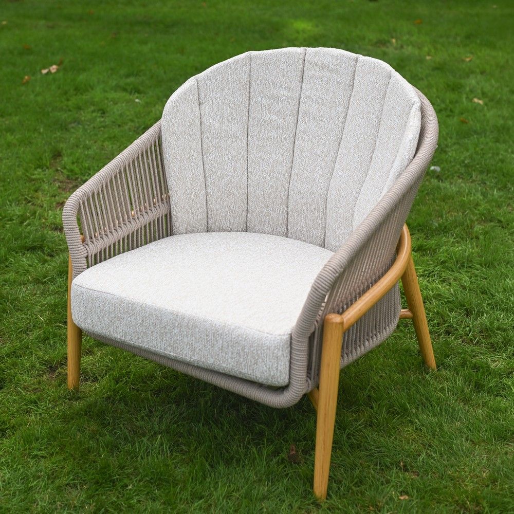 The Soria Woven 4-Piece Outdoor Lounge Set Showing a one of the Chairs on a Garden Lawn