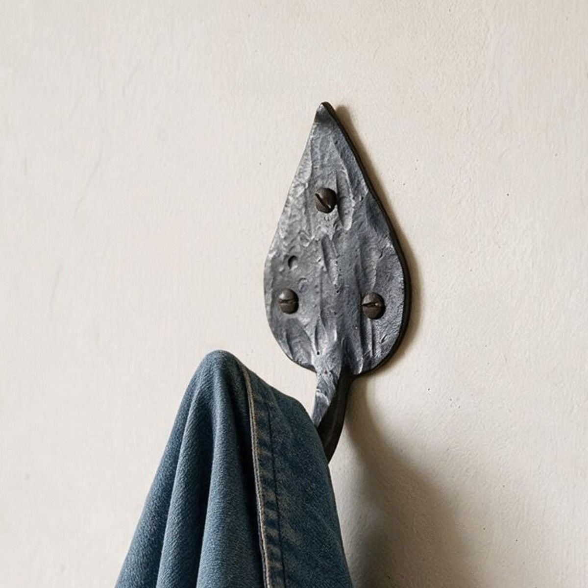 The Steel Leaf Shaped Hook Shown Close Up on a Cream Coloured Wall - Digital Illustration 