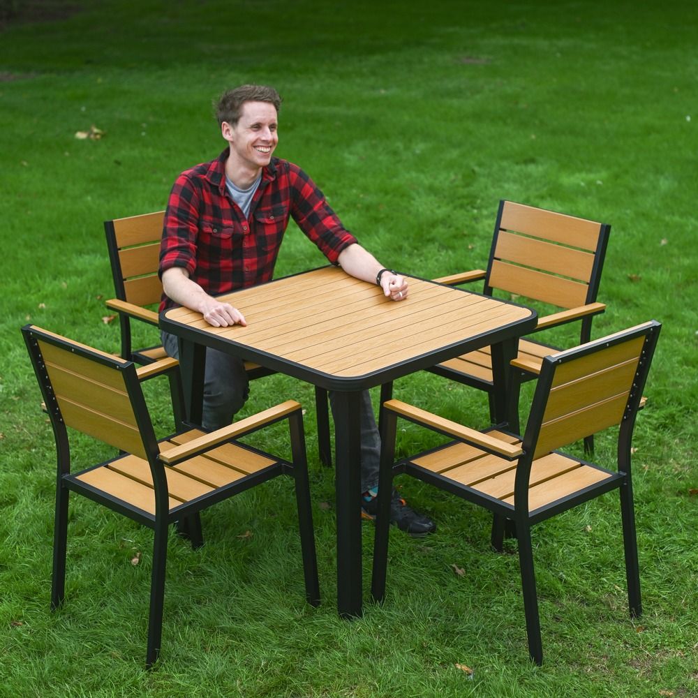 The Strata Slatted 4-Seater Outdoor Dining Set in Black With a Smiling Man Sat on one of the Chairs
