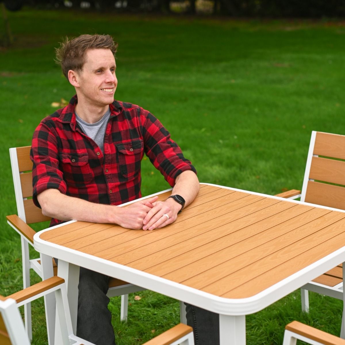 The Strata Slatted 4-Seater Outdoor Dining Set With a Smiling Man Relaxing at the Table