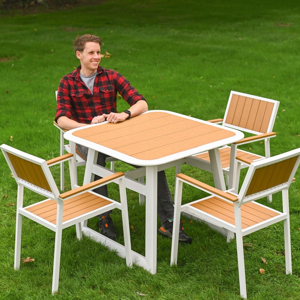 The Verve Quadrat 4 in Seater Outdoor Dining Set in White With a Man Sat at the Table Smiling