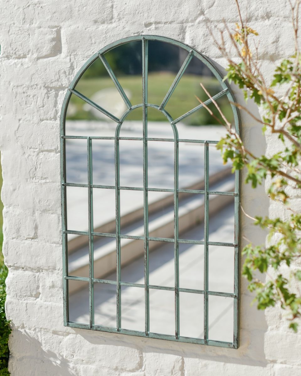 In situ photo of rustic green finish metal arched garden mirror