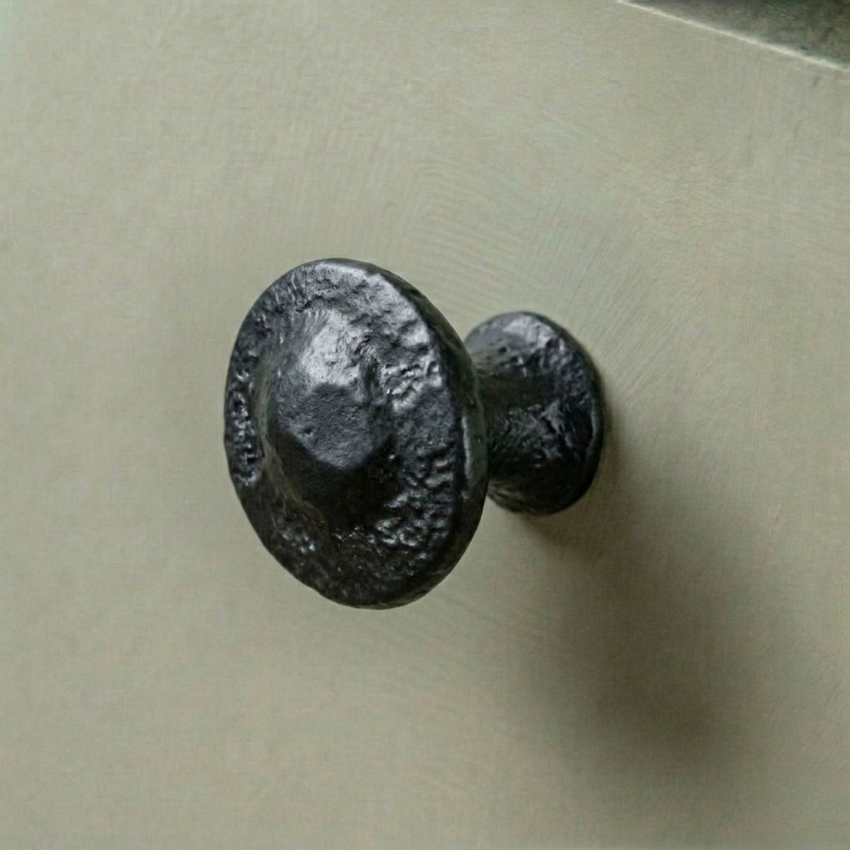 Traditional Black Iron Button Design Cabinet or Cupboard Knob Mounted on a Green Kitchen Cupboard Door - Digital Illustration 