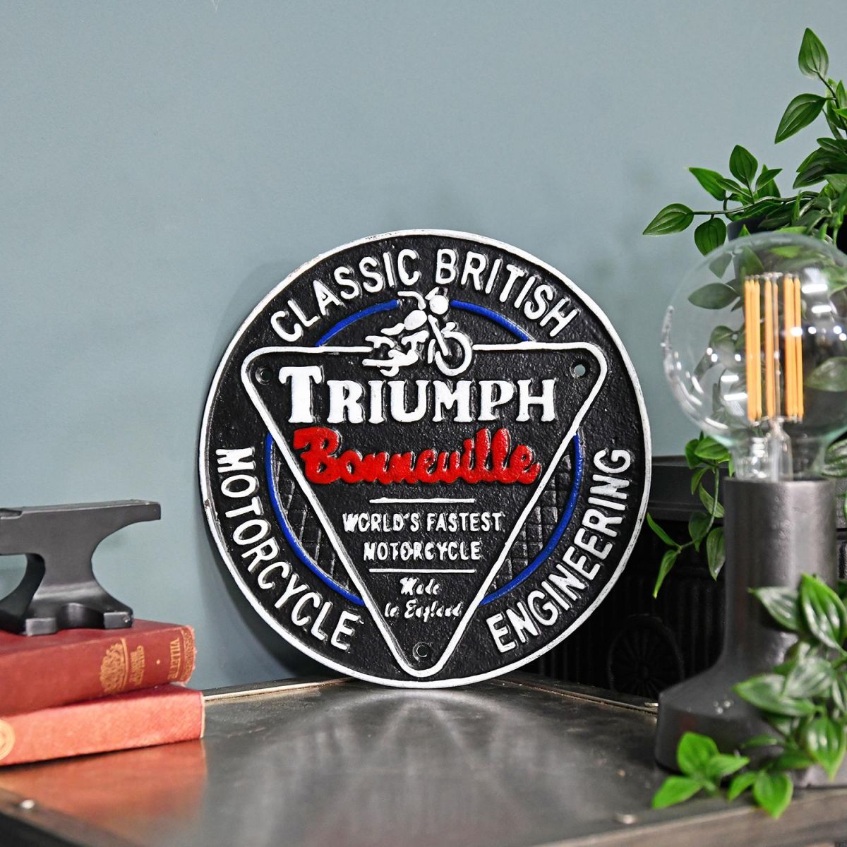 "Classic British Triumph Motorcycles" Cast Iron Vintage Wall Sign Next to a Blue Modern Wall