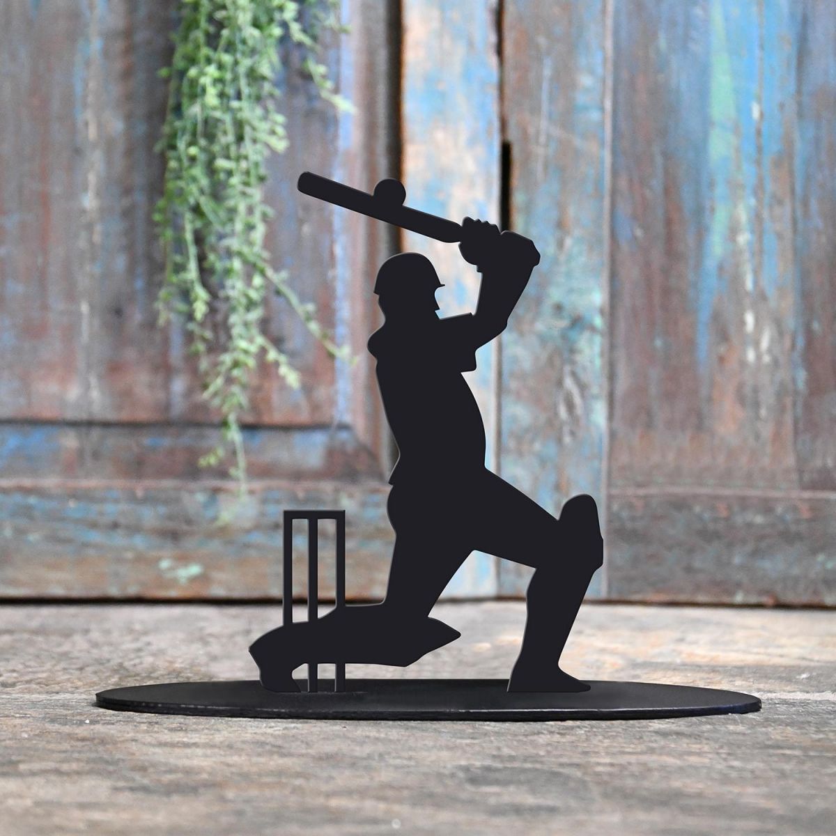 Cricket Player Iron Door Stop Next to a Rustic Blue Door
