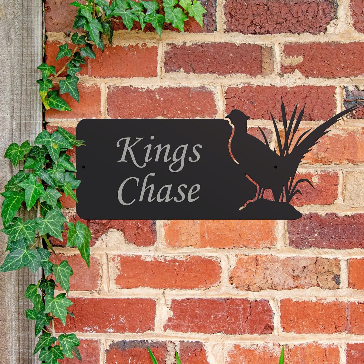 Pheasant Iron House Name Sign Mounted o a Brick Wall