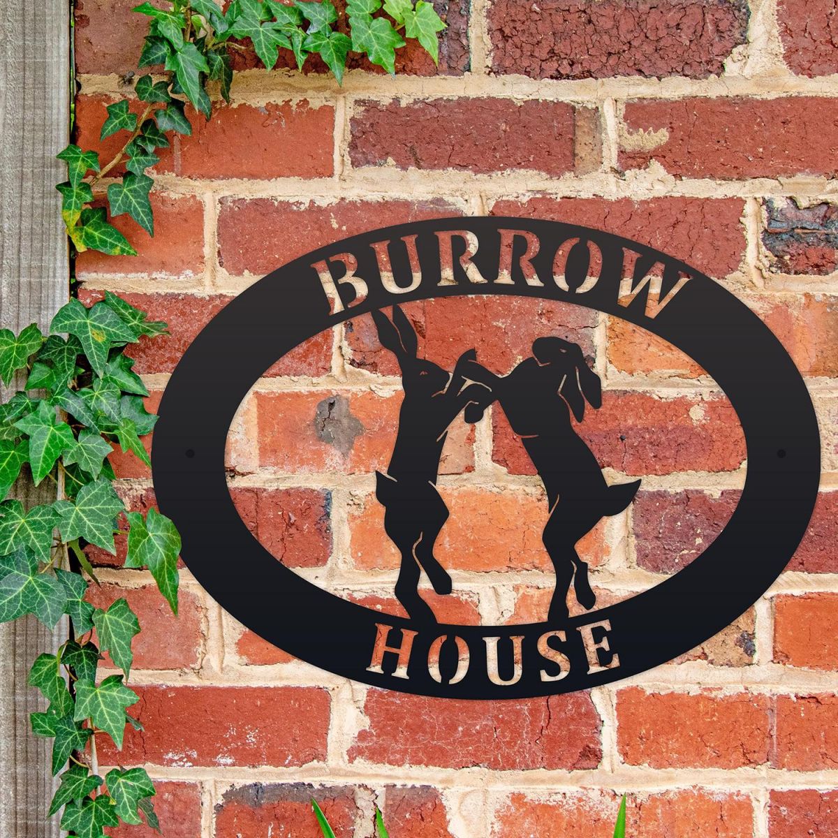 Boxing Hares Iron Oval House Sign on a Brick Wall