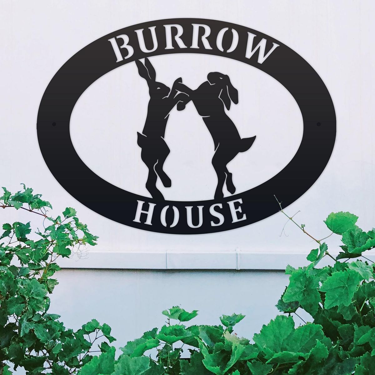 Boxing Hares Iron Oval House Sign on a White Wall