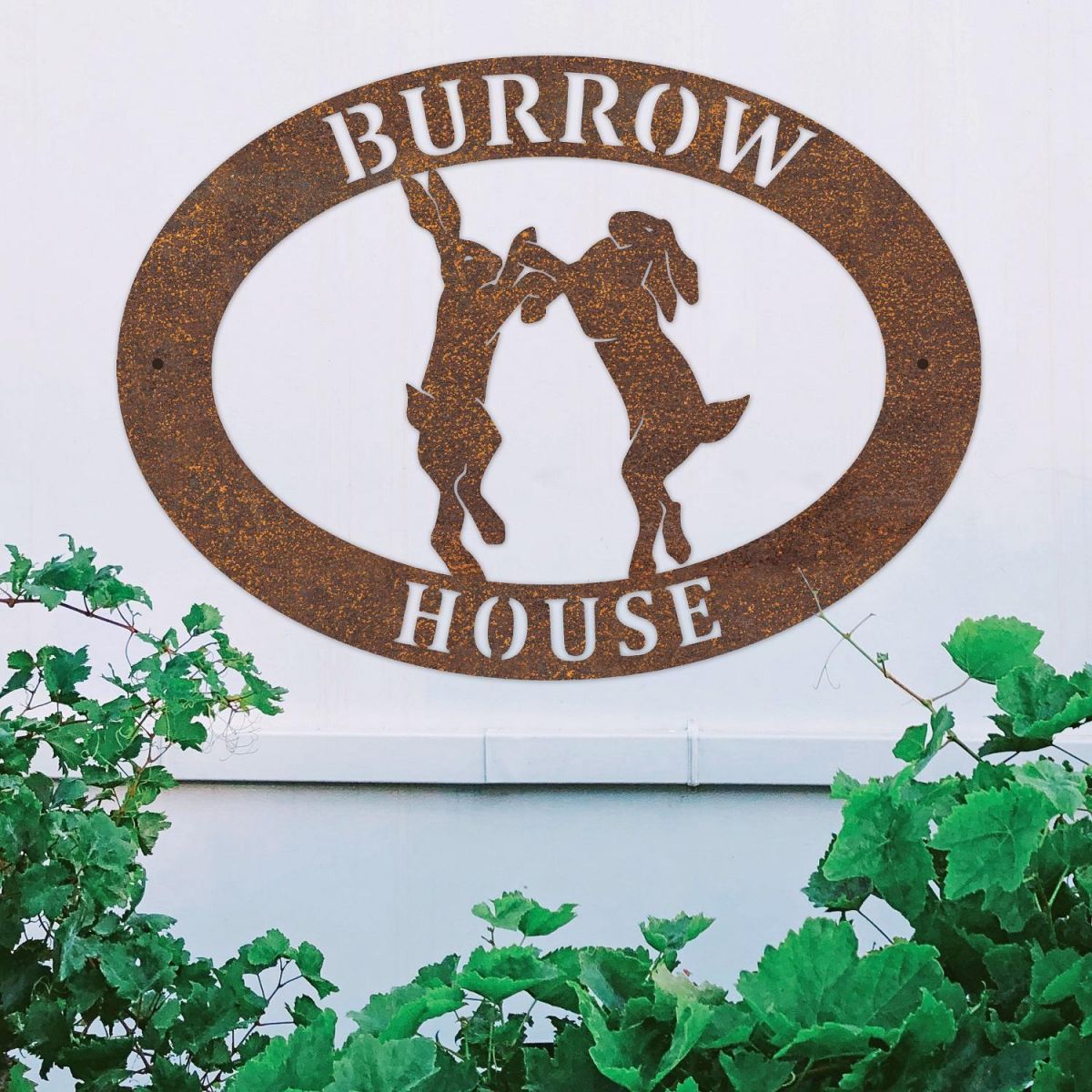 Boxing Hares Iron Oval House Sign on a White Wall