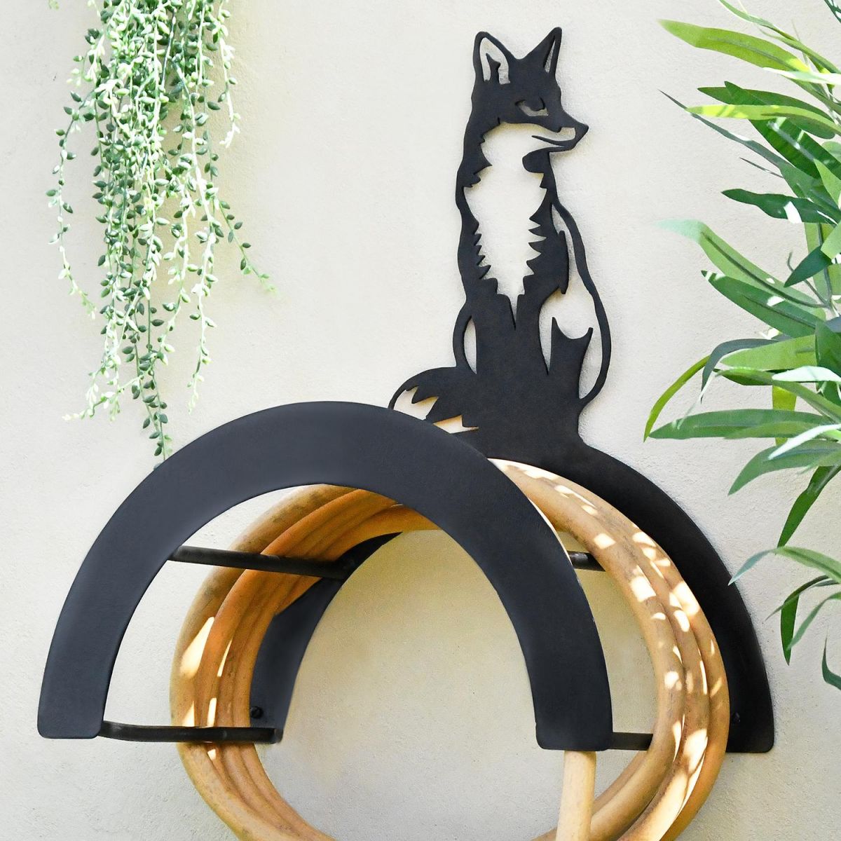 Wall Mounted Sitting Fox Iron Hose Holder Mounted to a Grey Garden Wall