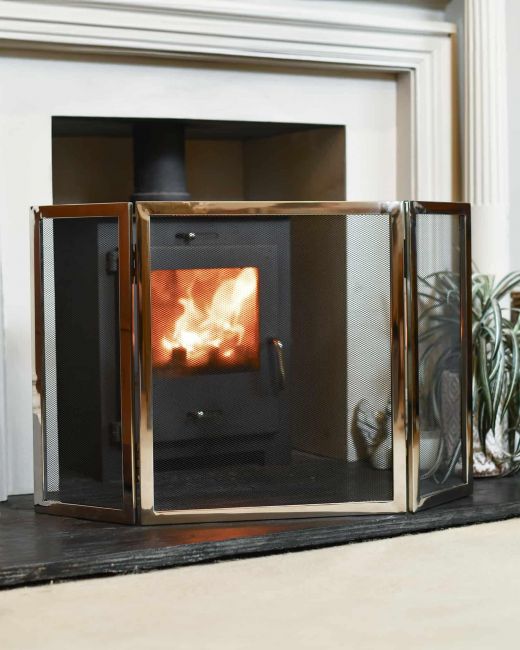 Polished steel fireguard in front of log burner Polished steel fireguard in front of log burner