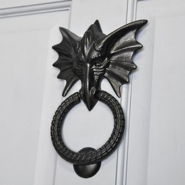 Brass dragon door knocker on grey door