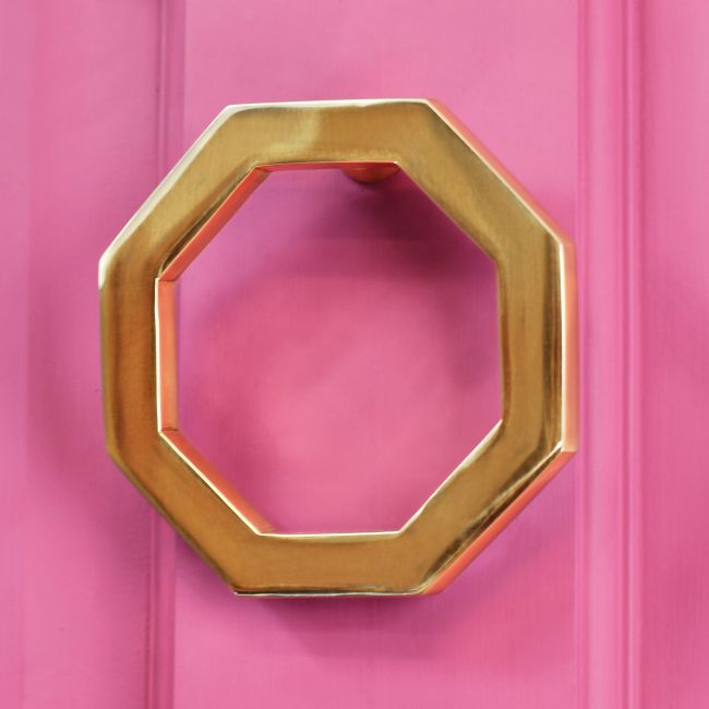 Polished brass Octagonal door knocker on pink door Polished brass Octagonal door knocker on pink door