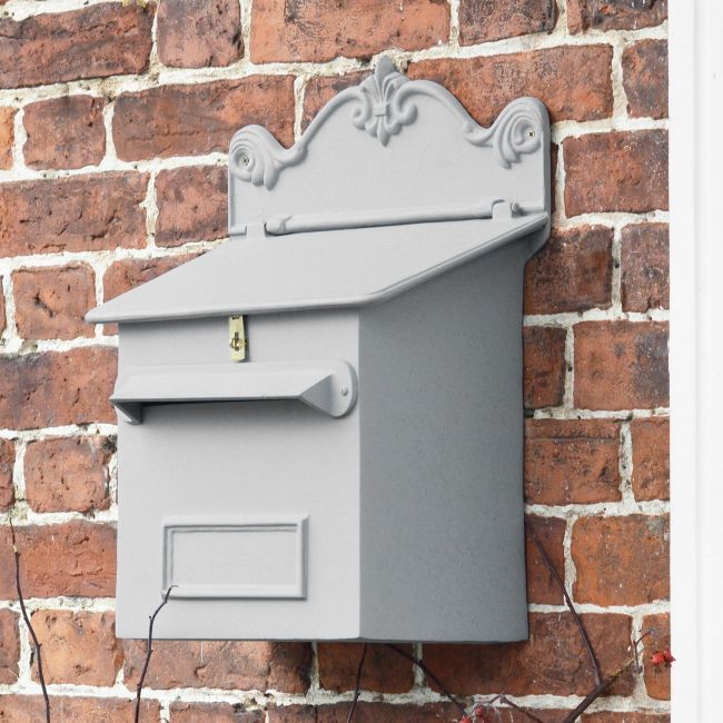 Grey Wall Mounted Post box on outside brick wall