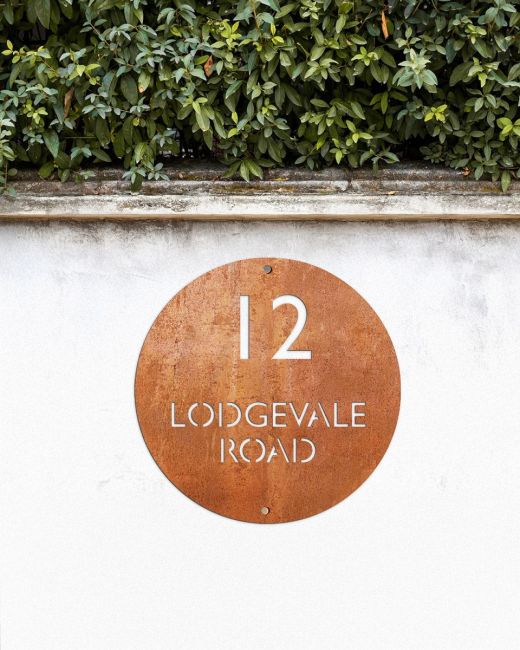 Modern Circular House Sign in Situ on a White Garden Wall Modern Circular House Sign in Situ on a White Garden Wall